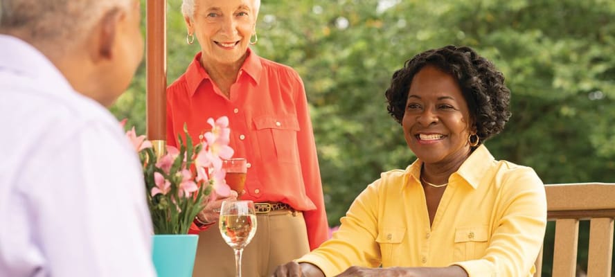 Two smiling women enjoying a chat outdoors with flowers