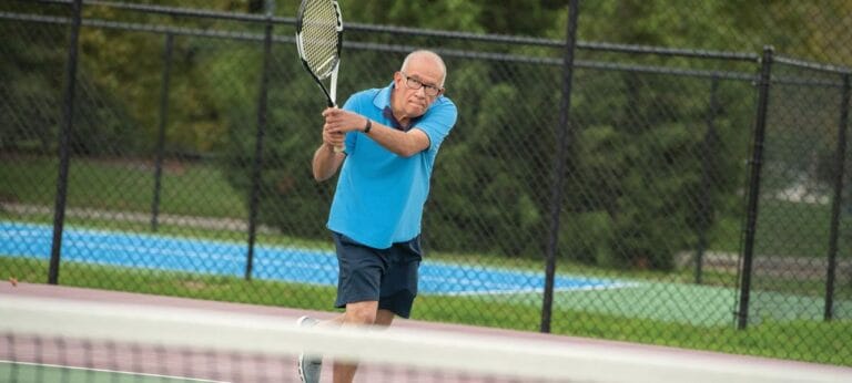 Resident enjoying a game of tennis outdoors