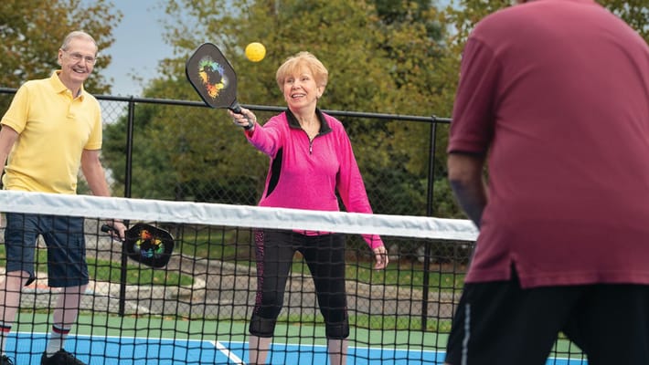 Seniors playing pickleball on an outdoor court