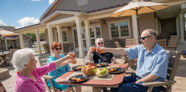 Residents enjoying a meal outdoors, toasting with drinks