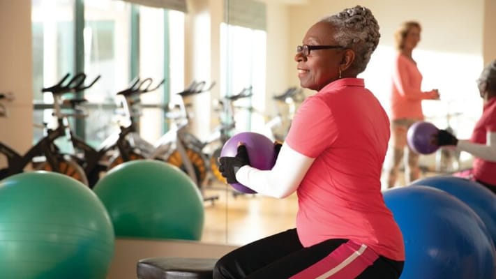 Residents participating in an exercise class with fitness equipment