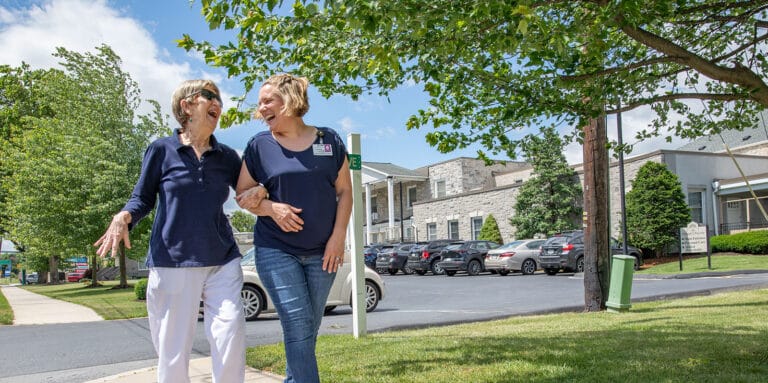 Staff and resident walking outside near the building