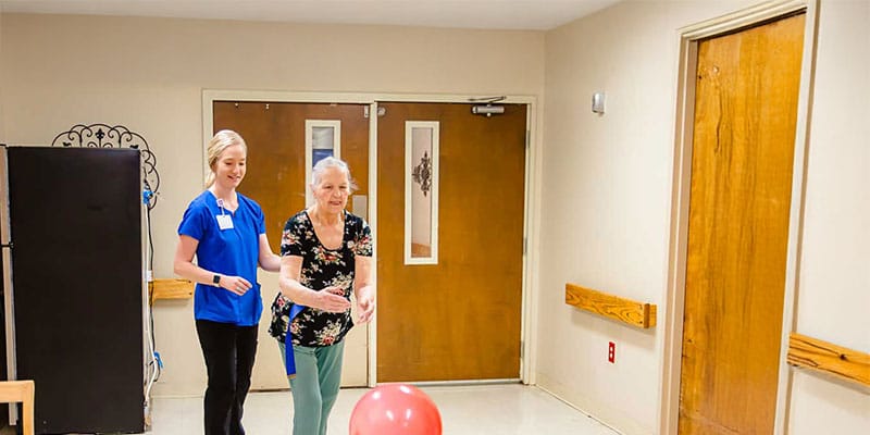 Staff member and resident engaging with a balloon in an activity area