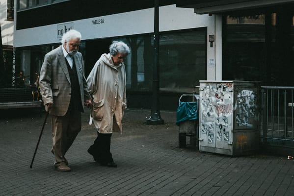 An elderly couple walking hand in hand outdoors
