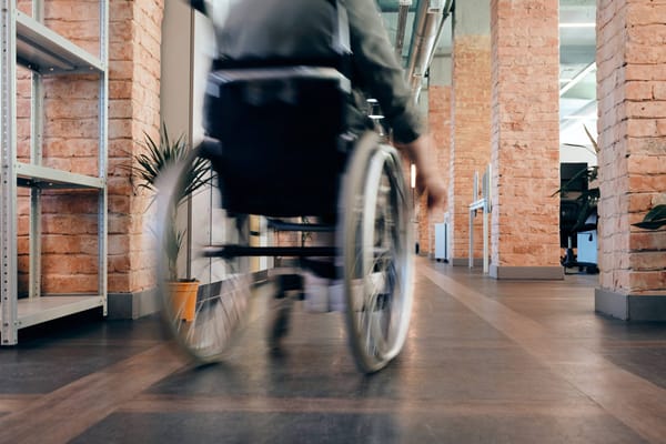 Resident in a wheelchair moving through a facility interior