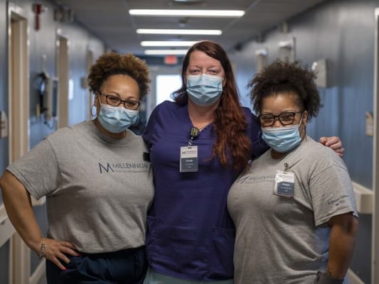 Three staff members wearing masks in a hallway