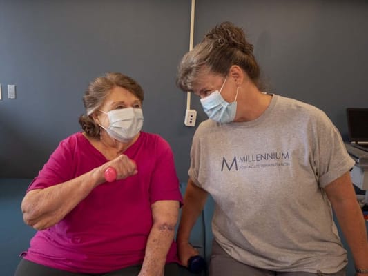 Resident and staff member engaging in exercise with weights