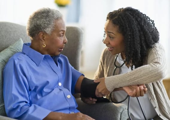 A caregiver taking a resident's blood pressure in a cozy setting.