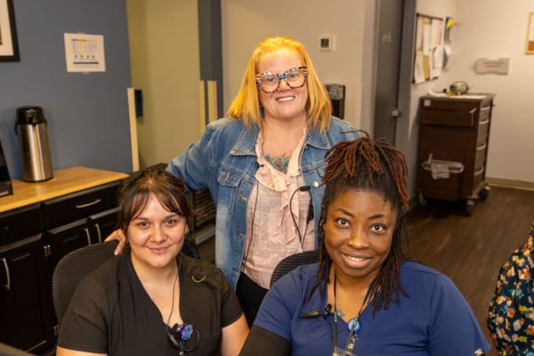 Three staff members smiling at a reception area