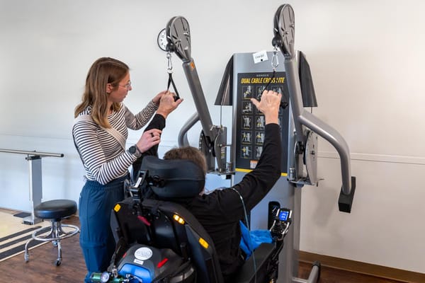 A therapist assisting a resident with a strength training machine