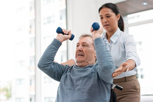A staff member assisting a resident with weights in a rehab session