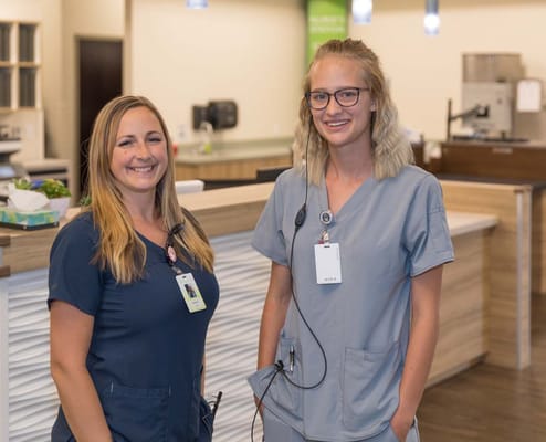 Two staff members smiling in a facility common area