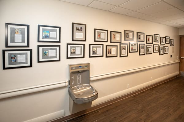 Framed photos and information displayed on a wall in a hallway