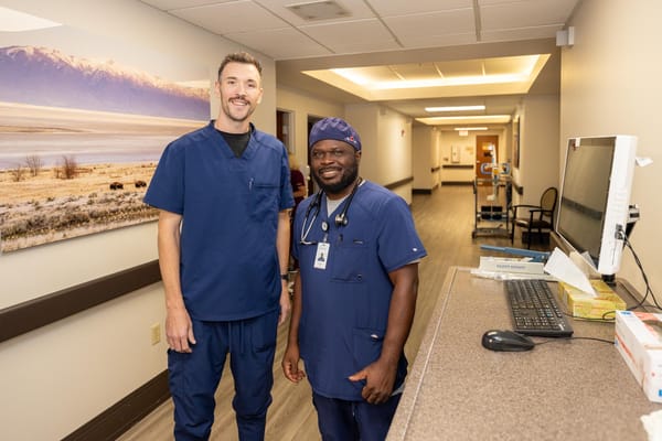 Two healthcare staff members smiling in a facility hallway