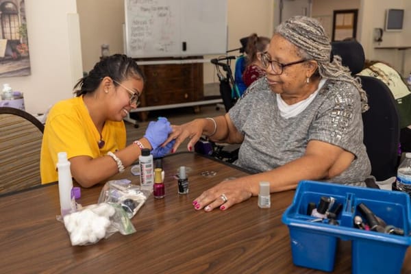Resident receiving a manicure from a volunteer