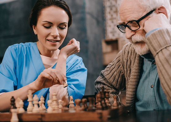 A staff member and resident playing chess in a common area