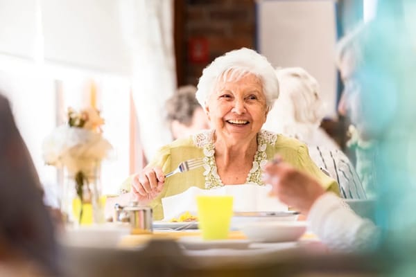 A smiling resident enjoying a meal in the dining area