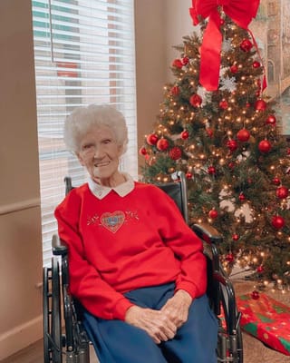 Senior resident smiling by a decorated Christmas tree