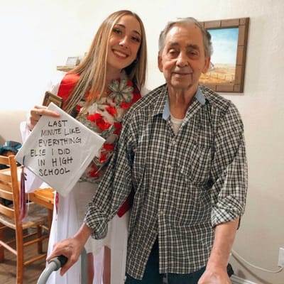 Resident and staff member posing together with a sign