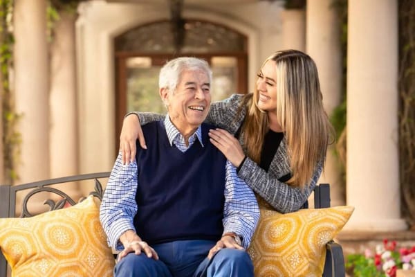 Resident smiling with staff in a garden setting