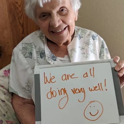 Senior resident holding a message board with a positive note