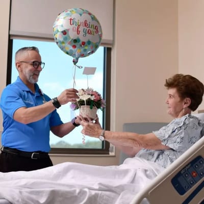 Staff delivering flowers and a balloon to a resident