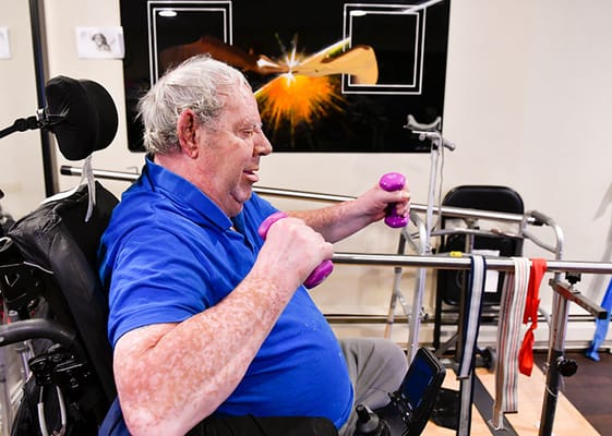 A resident exercising with weights in a therapy room