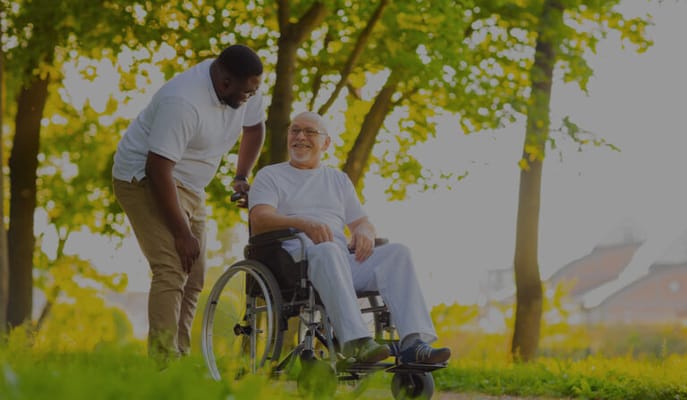 Care staff assisting a resident in a wheelchair outdoors