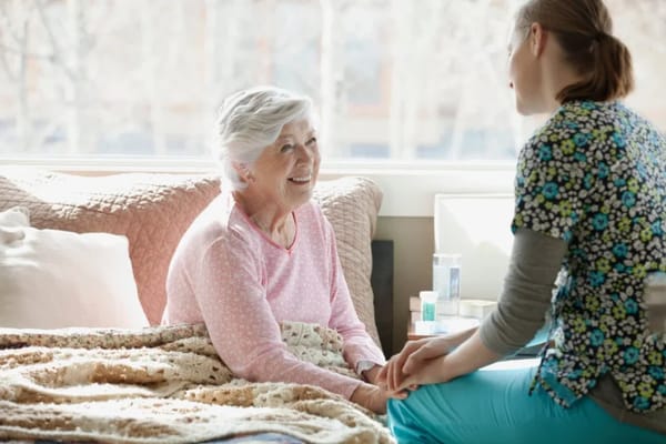 A caregiver and elderly woman sharing a moment indoors