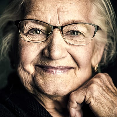 Close-up portrait of an elderly woman with glasses and a warm smile