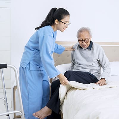 Staff assisting an elderly resident in a bedroom