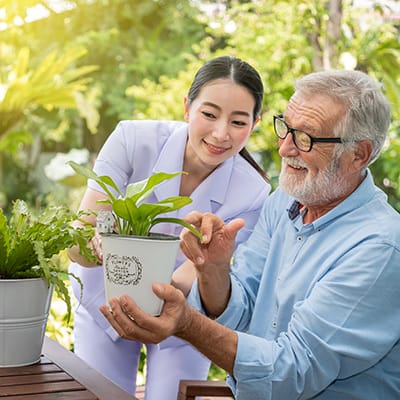 Care staff helping a resident with a plant outdoors