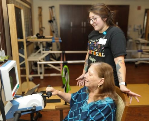 Resident engaging in a therapy activity with staff support