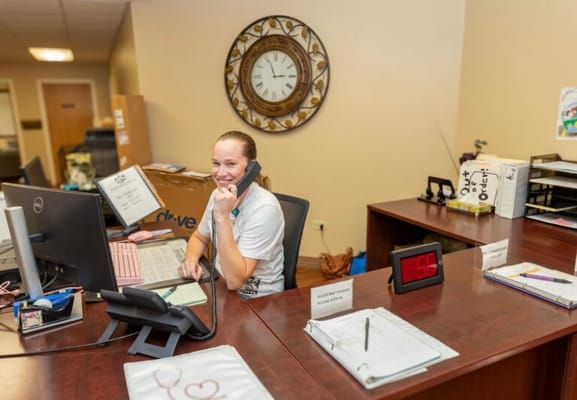 Receptionist at a desk answering a phone call