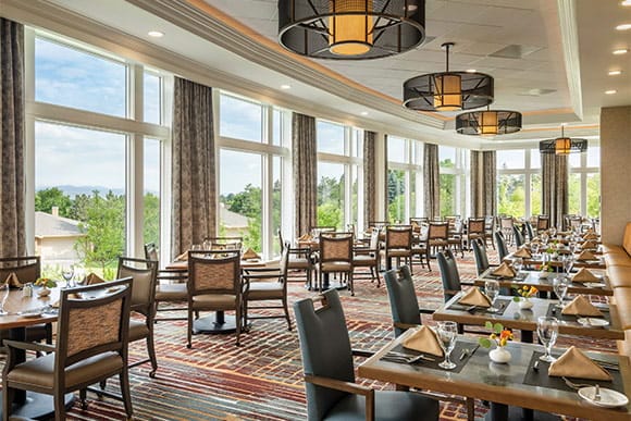 Bright dining room with large windows and tables set for dining