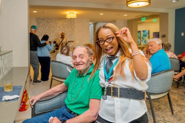 Resident enjoying activities with staff in a common area