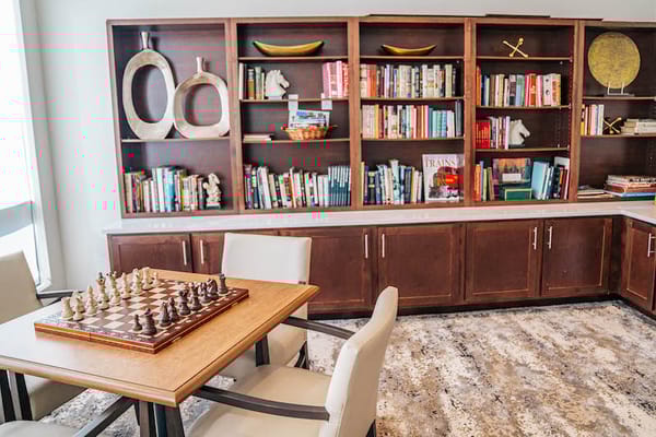 Interior view of a common area with a chessboard and bookshelves