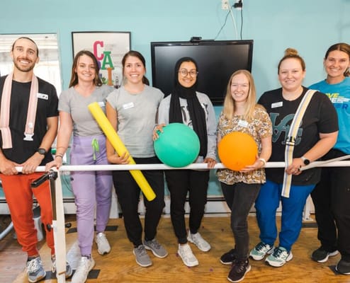 Staff members holding fitness equipment in an activity room