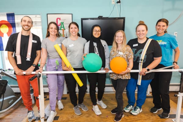 Staff members posing with exercise equipment in an activity room