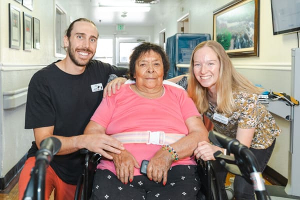 Two staff members with a resident in a hallway