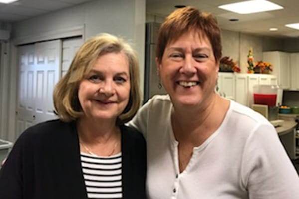 Two smiling staff members in a common area