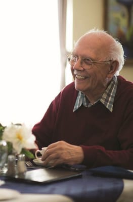 A smiling elderly man enjoying a cup of coffee