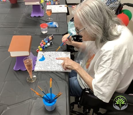Resident painting at a communal activity table