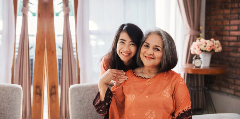 A woman and her caregiver smiling in a living area