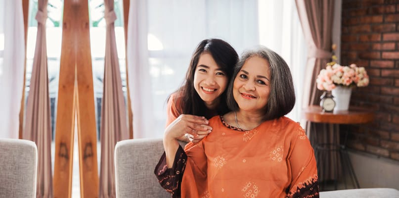 A woman and her caregiver smiling in a living area