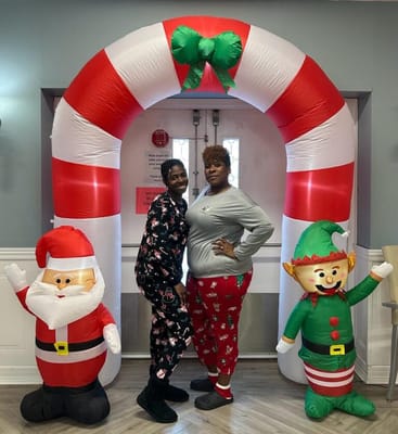 Two staff members posing in festive outfits at a holiday event
