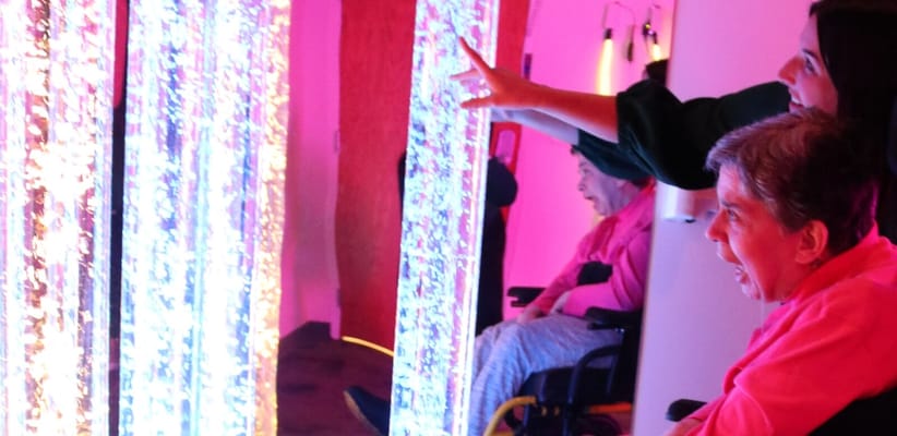 Residents engaged with sensory equipment in a vibrant room
