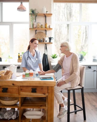 Nurse taking a resident's blood pressure in the kitchen
