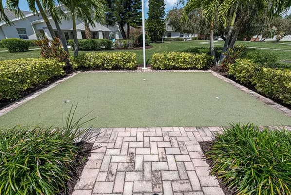 Outdoor putting green surrounded by landscaping