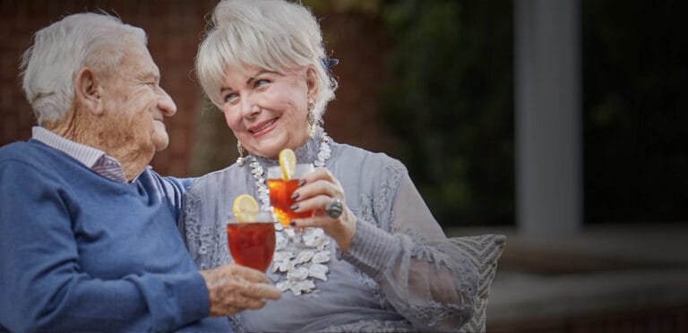 An elderly couple enjoying drinks together outdoors